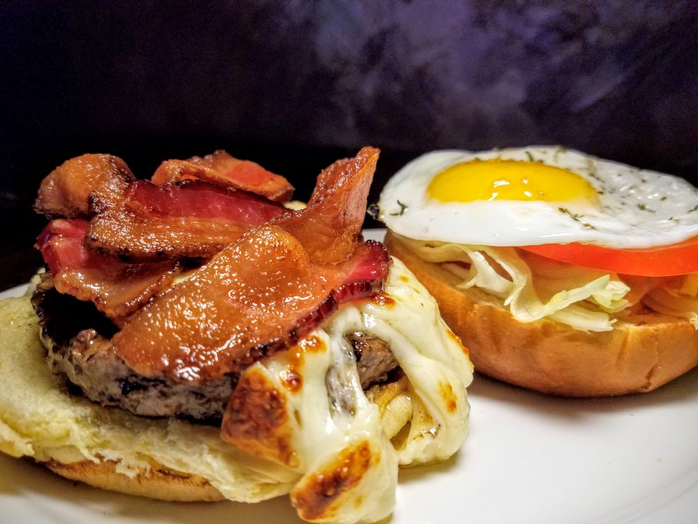A generous heap of bacon, melted cheddar cheese, and a fried egg adorn the 'Thief Burger'.