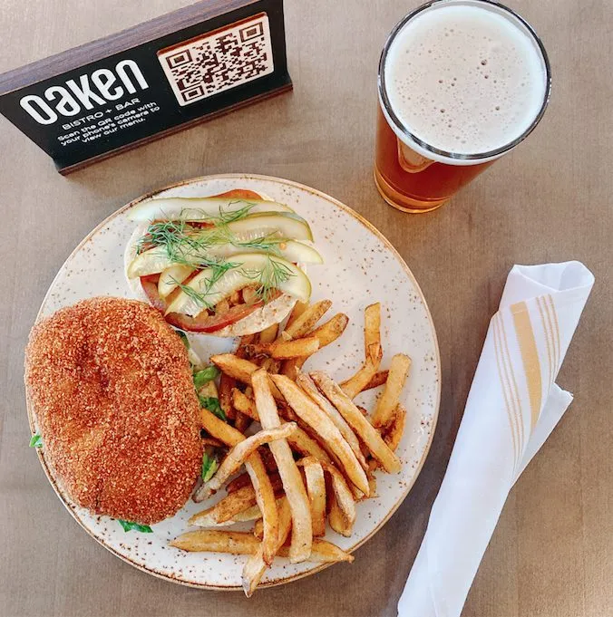 Diners may order the Indy 500 Pork Tenderloin, served with picnic pickles, dill aioili on a fresh potato bun alongside house fries. (Photo courtesy of Oaken Bistro) for Memorial Day Specials in Chicago