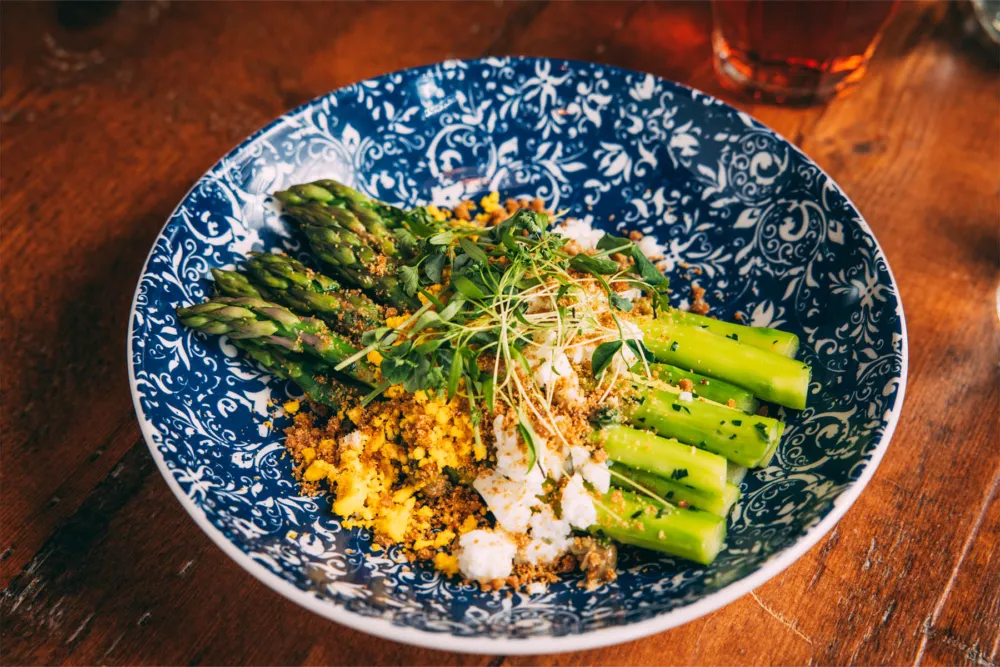 Asparagus Mimosa: chilled asparagus, hard cooked egg, dijon vinaigrette, salumi breadcrumbs, capers, herbs for Lardon Expands Culinary Offerings, Announces New Executive Chef