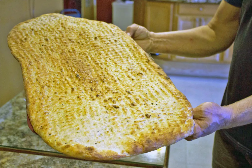 Nasir holds freshly baked bread. Photo: Sarah Conway. for Where Chicago and Afghanistan Meet: Albany Park's Afghan Kabob Serves More than Dumplings