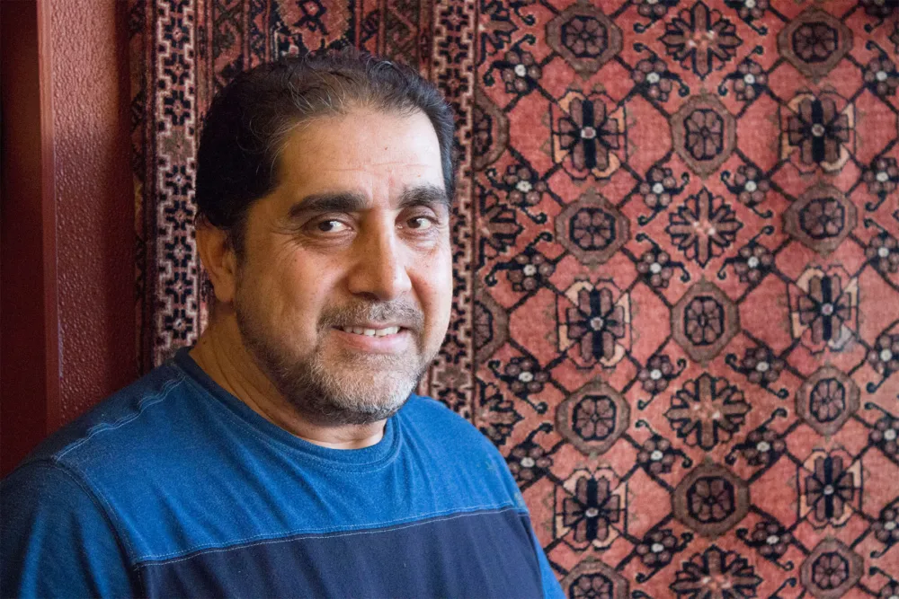 Nasir Raufi, owner of Albany Park’s Afghan Kabob, in front of one of several traditional carpets in his restaurant. Photo: Sarah Conway. for Where Chicago and Afghanistan Meet: Albany Park's Afghan Kabob Serves More than Dumplings