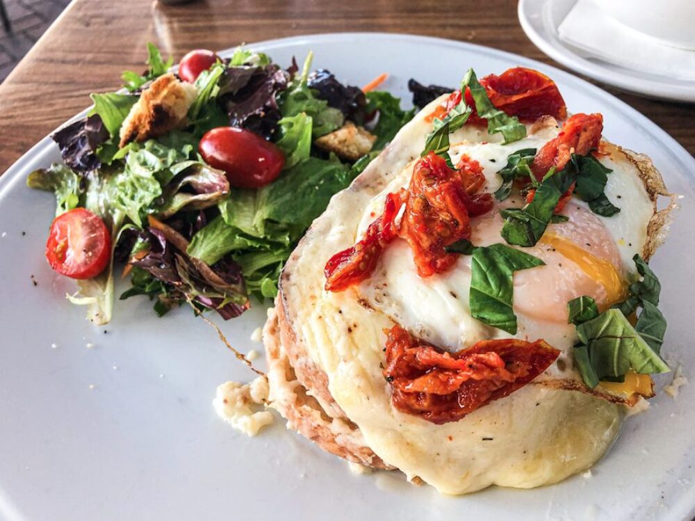 This Croque Madam panini requires a fork and knife to eat. Salty prosciutto shares the spotlight with a blanket of buttery fontina béchamel. Served with a sunny side egg. for Weekend Brunch is Back at Frasca Pizzeria Featuring Bottomless Aperol Spritz’, Rose Sangria and Mimosas
